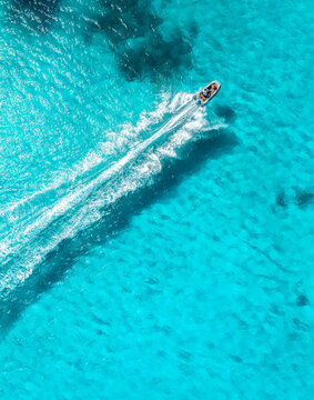 Aerial drone view of floating speed boat in blue sea on sunny day. Summer vacation. Mallorca island, Spain. Top down view of boat, sea, turquoise water. Travel. Tropical landscape. Yachting. Cruise