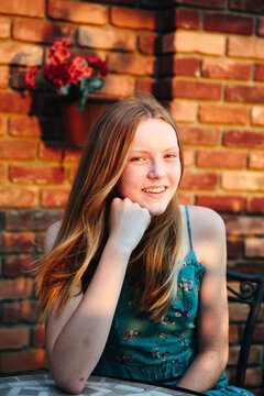 Girl posing a table with brick wall behind her 