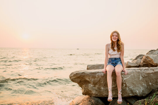 Girl sitting on rocks by lake