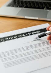 Obraz premium Close-up of a hand holding a pen to sign a petition for divorce legal document on a wooden desk