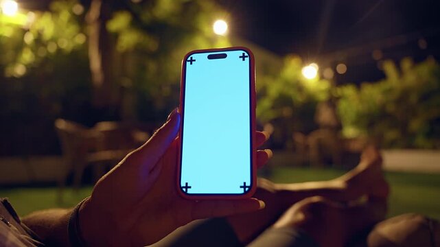 Hand Holding Smartphone With Blank Screen Mockup at Night in Tropical Garden, Mobile Communication and Digital Lifestyle