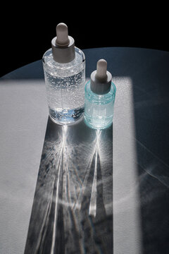 Skincare serum glass bottles casting beautiful light patterns and shadow on table