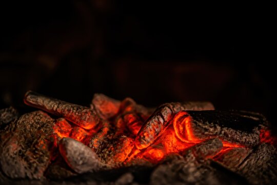 Glowing embers of burning coals emitting heat and light in a dark setting