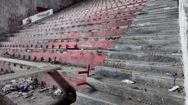 Abandoned palace, derelict concrete stadium steps and damaged seats.