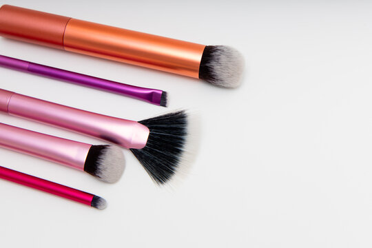 Selection of makeup brushes arranged in a line on a plain surface in a bright workspace