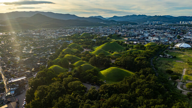 Aerial view of the historic Daereungwon Tomb Complex with its iconic green burial mounds surrounded by the urban landscape of Gyeongju-si, Gyeongsangbuk-do, South Korea.