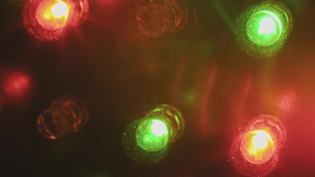 Top-down macro of pulsing RGB diode lights showing scattered red, green, and blue bulbs. Vibrant color flares and particle effects on a dark surface create a dynamic, abstract pattern.