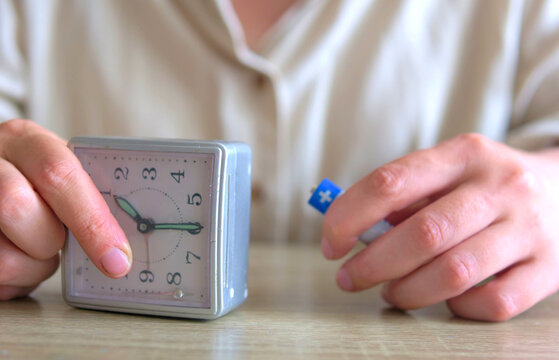 Woman holding an alarm clock and a battery representing time management, energy levels, and burnout