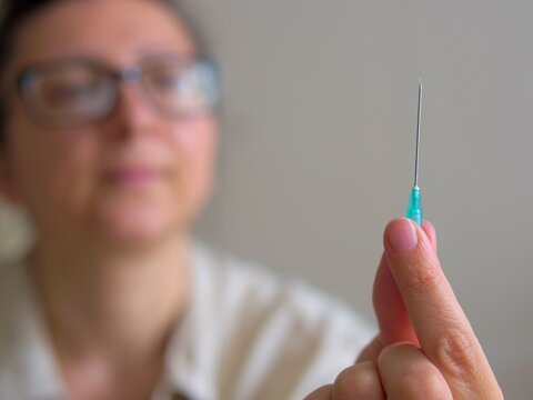 woman holding a sharp hypodermic needle for an injection before a vaccination, treatment, or insulin dose