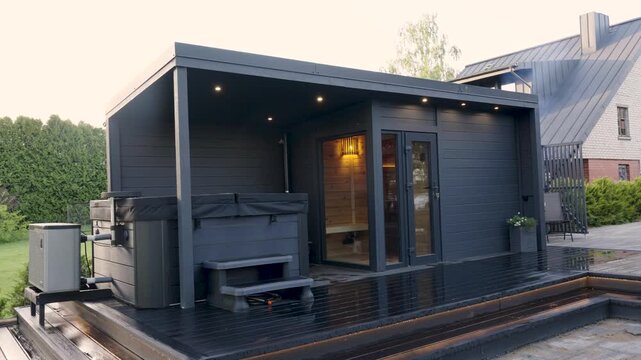 Modern wooden sauna with hot tub and outdoor deck in a serene garden setting, showcasing sleek design and cozy ambiance