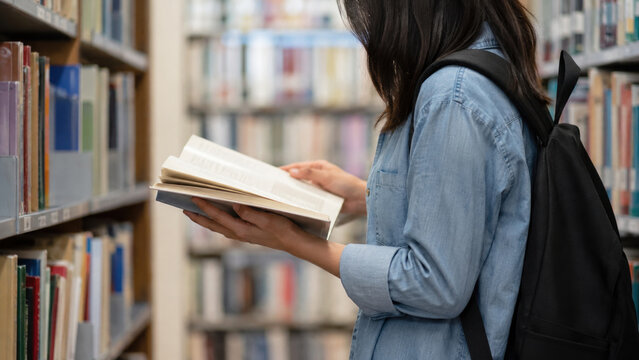 Woman Reading Book in Library Aisle