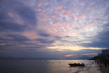 Obraz premium Sunset Beach with Boat and Dramatic Cloudy Sky