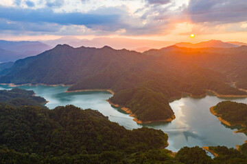 Naklejka premium Sunset Over Mountain Lake and Forested Hills