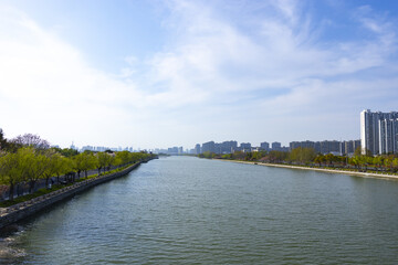 Obraz premium Urban riverfront with city skyline under a blue sky