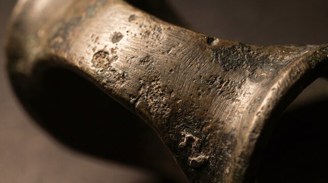 Macro close up of a heavily weathered and textured ancient bronze artifact with signs of oxidation