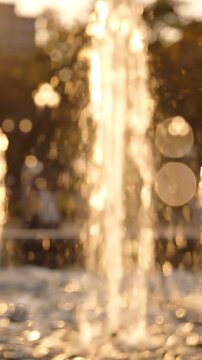 A Serene Evening at the Fountain: Capturing the Glimmering Water Flows in Soft Focus, Bathed in Golden Sunset Light for a Tranquil Atmosphere
