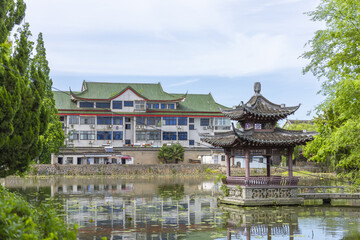 Fototapeta premium Traditional Chinese Pavilion by a Reflective Pond in a Green Park