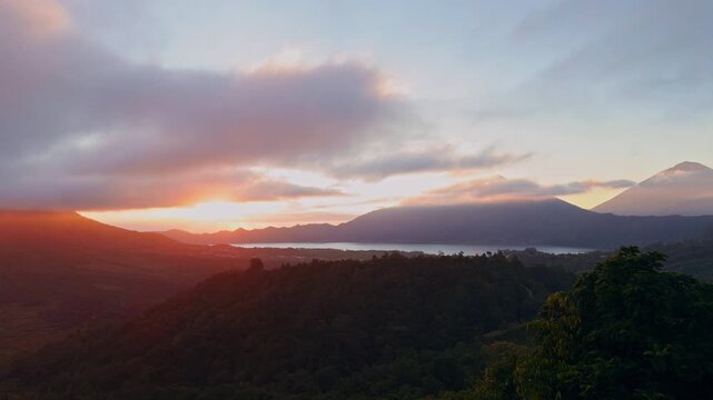 Spectacular Sunrise Above Mount Abang And Gunung Batur, Golden Light Breaks Through Dramatic Clouds Over Lake Batur And Dense Tropical Forested Highlands
