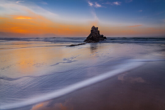 Beautiful long exposure seascape of flysch rock formations at Sopelana beach during a colorful sunset with silky water in the Basque Country, Spain