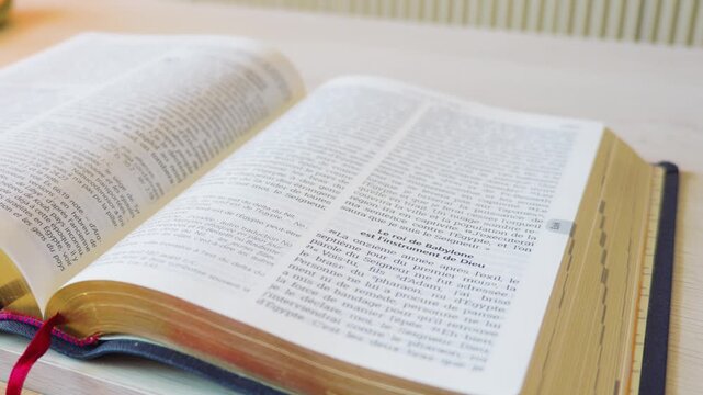Open French holy bible book with ribbon markers on table