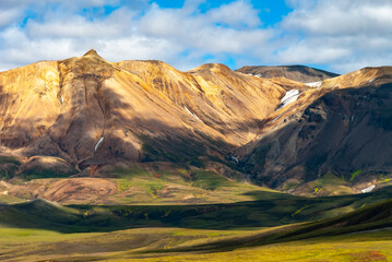 Fototapeta premium Winding glacial stream in the Icelandic Highlands with dramatic volcanic mountains vast wilderness and colorful summer landscape