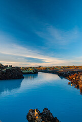Fototapeta premium Volcanic lava formations beside the Blue Lagoon in Iceland with vivid moss colorful geothermal landscape and crystal blue water