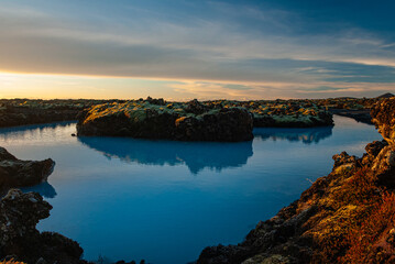 Fototapeta premium Volcanic lava formations beside the Blue Lagoon in Iceland with vivid moss colorful geothermal landscape and crystal blue water