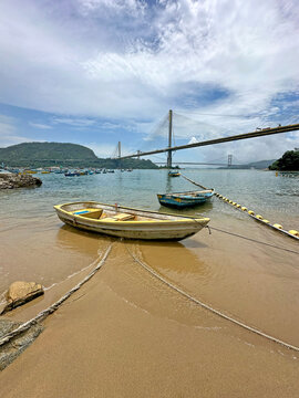 Serene coastal view with boats and bridge under a cloudy sky