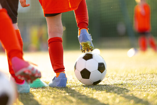Close-Up of Kids Soccer Cleats and Ball: Young Player Stepping on Football to Control It