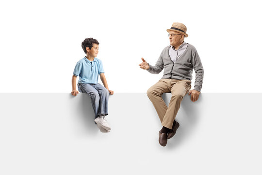 Grandfather and grandson sitting on a white panel and talking to each other