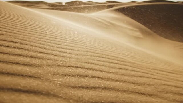 A close-up perspective of wind-swept sand dunes in a desert, with fine sand particles visibly lifted and carried by the wind, creating a hazy, dynamic effect against the soft contours of the landscape