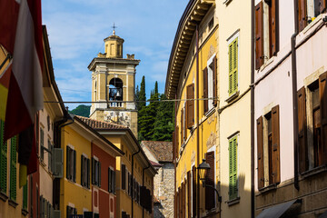 Fototapeta premium Bell tower of the Chiesa di San Francesco framed by an alleyway in the historic center of Gargnano, Lombardy