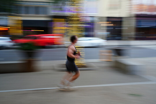 A man running in downtown Raleigh, North Carolina.  Panning slow shutter speed showing motion blu
