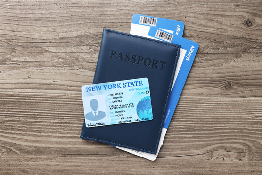 Driver's licence and passport with tickets on wooden background, top view