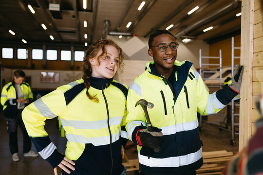 Female and male student wearing reflective jacket studying civil engineering in vocational workshop