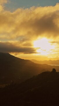 Vertical video. Timelapse Sunrise Above Gunung Batur and Gunung Abang With Golden Clouds Illuminating Volcanic Landscape and Misty Mountain Horizon