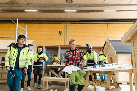 Young students following senior male teacher in workshop for construction training at vocational school