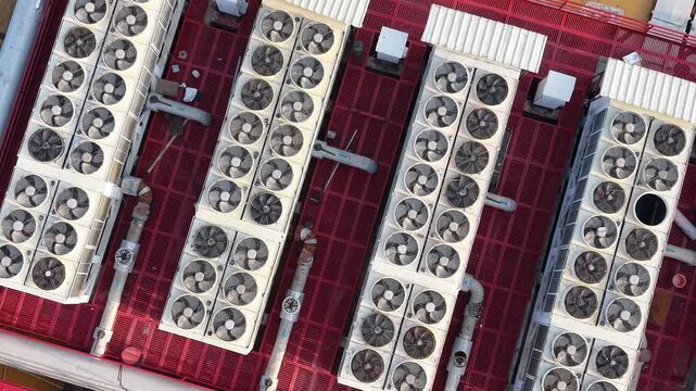 Top down aerial of rows of rooftop HVAC cooling units on a large industrial building