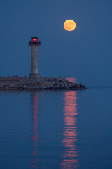 Fototapeta premium Full strawberry moon rising behind Trakata lighthouse near Euxinograd in Varna Bulgaria