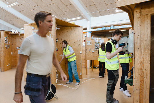 Male and female students learning to repair electrical outlets in training center at vocational workshop
