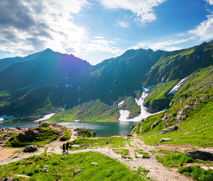 beautiful alpine scenery of fagaras mountains. balea lake in romania mountain landscape. summer weather with clouds on sky. view of rippled water near rocky slope. remote wilderness travel background