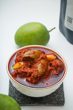 Styled bowl of mango pickle garnished with a fresh green mango
