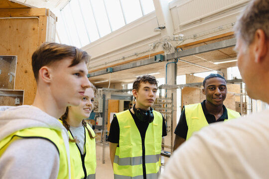 Yong vocational students listening to male teacher giving instructions at civil engineering workshop