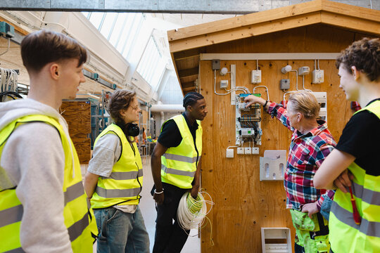 Senior male engineer teaching students about electric components of circuit in training session at vocational workshop