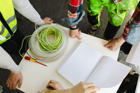 High angle view of students and teacher reviewing open technical manual with electrical diagrams in book at classroom ta