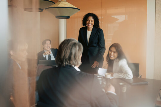 Smiling female entrepreneur talking with business partner in meeting at office board room