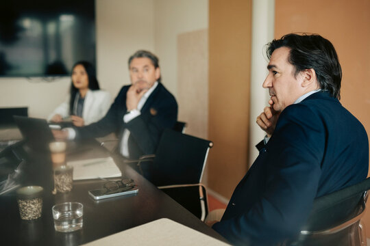 Male white collar expert sitting at conference table in office business meeting