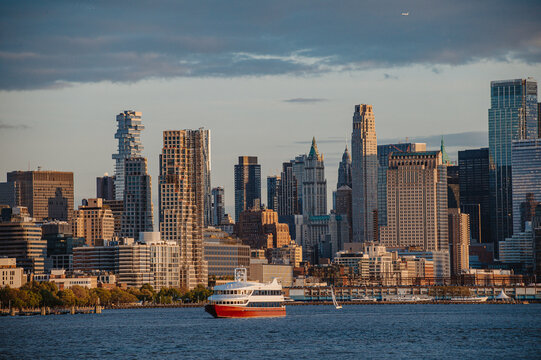 Lower Manhattan skyline with a passenger ferry boat. View of Tribeca skyscrapers including the Jenga tower from the Hudson River during afternoon light.