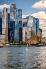 Fototapeta premium Sailboats near lightship on Hudson River, Manhattan skyline. Group of sailing vessels, red Frying Pan ship, glass skyscrapers, distant Empire State Building.