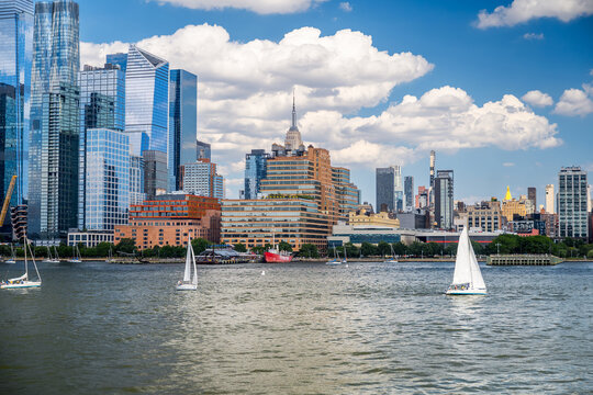 Sailboats crossing Hudson River near Empire State Building. Chelsea Piers waterfront, red lightship Frying Pan, brick warehouse, Manhattan skyline.